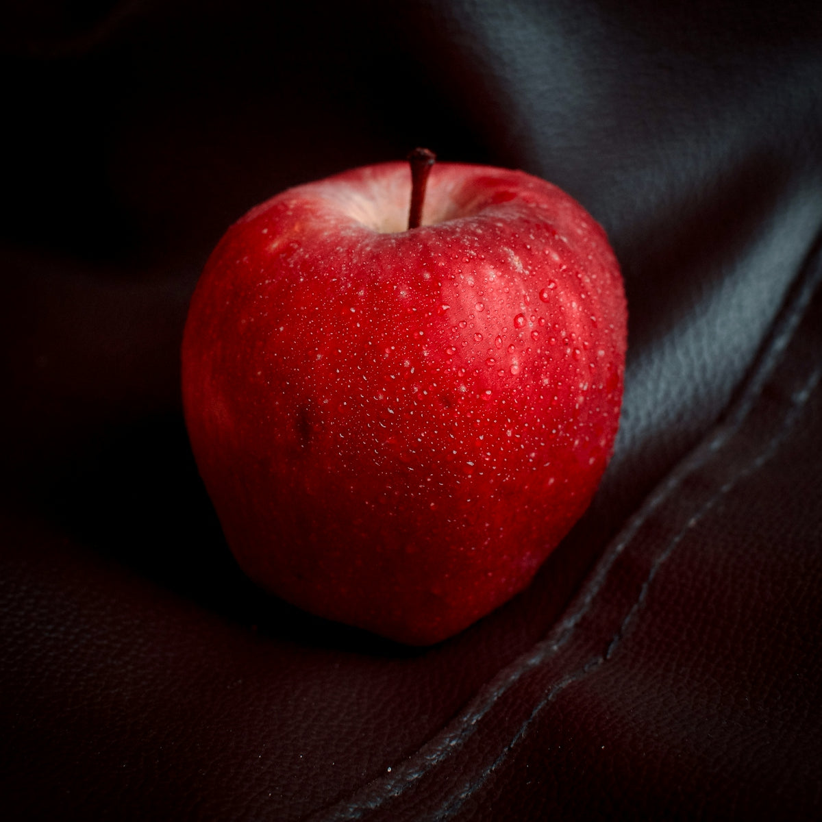 a red apple sitting on top of a black cloth