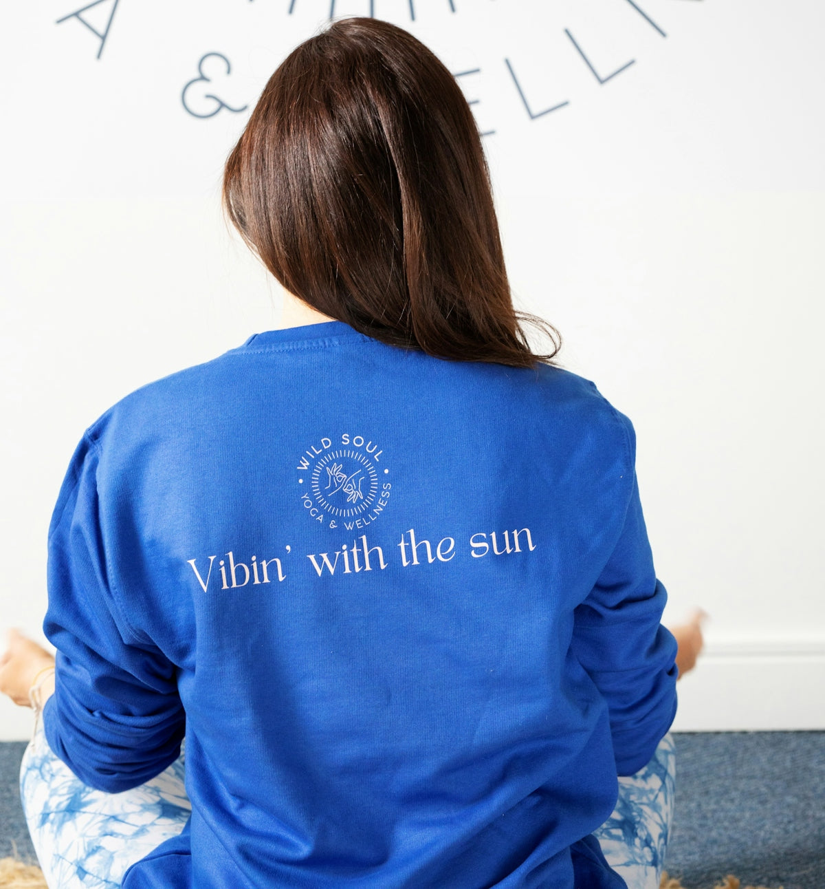 Woman in blue sweatshirt meditating indoors